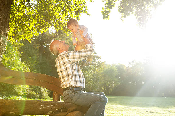 grandfather with grandson in park Playful grandfather spending time with his grandson in park on sunny day old man baby stock pictures, royalty-free photos & images