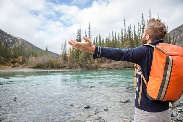 istock Young cheerful man by the river enjoying nature. 493030904