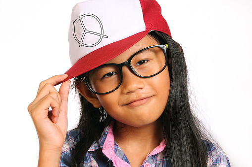 Little girl with glasses smiling and touching her hat isolated on white