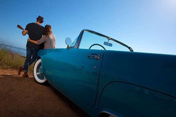istock Couple Looking at the Ocean by a Blue Convertible Car 493055340