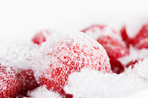 Strawberries, frozen for long time storage of ice and snow. It can be used as background. Isolated on white background
