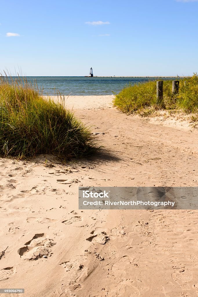 Ludington's North Breakwater Lighthouse A path leading to the beach with Ludington's North Breakwater Lighthouse against a clear blue sky in the background. Lighthouse Stock Photo