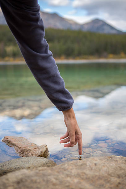 istock Finger touches surface of mountain lake 493061908