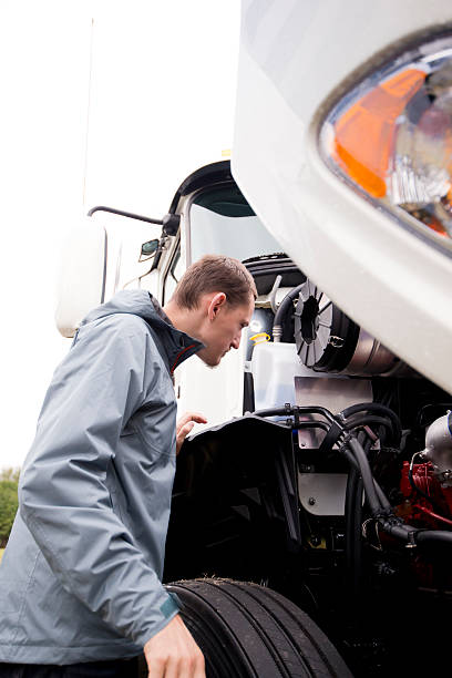 istock Truck driver inspecting white big rig semi truck engine 493063148