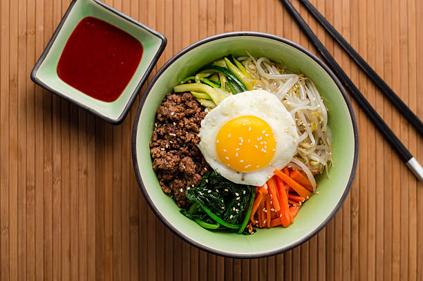 Korean Bibimbap Dish Bibimbap is a classic Korean dish, it's a bowl of rice topped with assorted seasoned vegetables and meat. To finish it off, a fried egg sits on top and a spicy chili sauce can be added. korea stock pictures, royalty-free photos & images