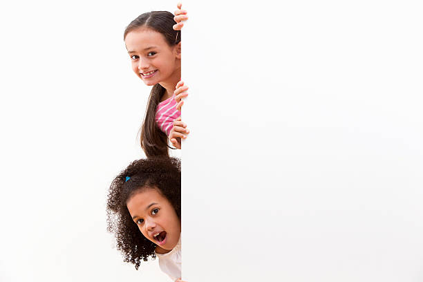 istock Two Cheeky Girls Looking Around White Wall In Studio 493070789