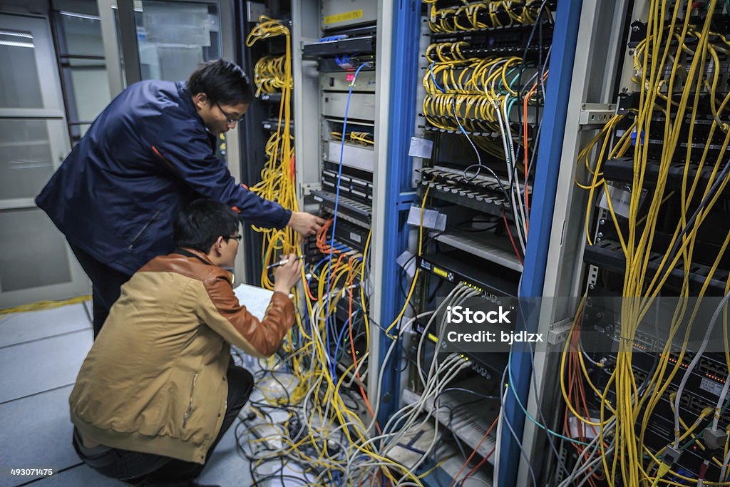 Due amministratori di rete sono al lavoro in sala server - Foto stock royalty-free di Adulto