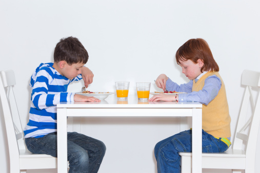 Studio Shot Of Two Boys Eating Breakfast Together