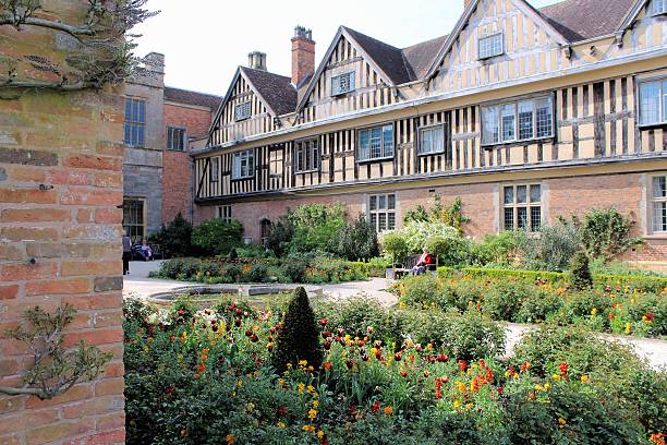 Coughton Court Coughton Court, Warwickshire, England - May 6, 2014: Tourists relaxing amongst flower beds in the Formal Garden at Coughton Court in Warwickshire, taken from outside the grounds coughton stock pictures, royalty-free photos & images