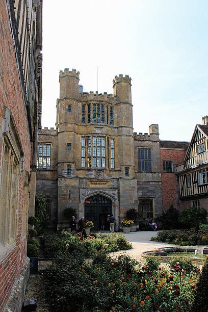 Coughton Court Coughton Court, Warwickshire, England - May 6, 2014: Tourists relaxing amongst flower beds in the Formal Garden at Coughton Court in Warwickshire, taken from outside the grounds coughton stock pictures, royalty-free photos & images