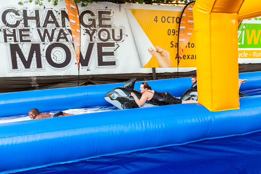 Sandton City, South Africa - October, 17th 2015: Children having fun, going down the Slide in Sandton City. Lady riding a dolphin lilo down the slide. This is a 300 metre slide in Sandton City centre, promoting walking in the city centre. South Africa's biggest slip and slide.