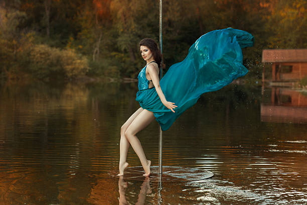 istock Girl dances a pole dance in the forest on lake. 493080508