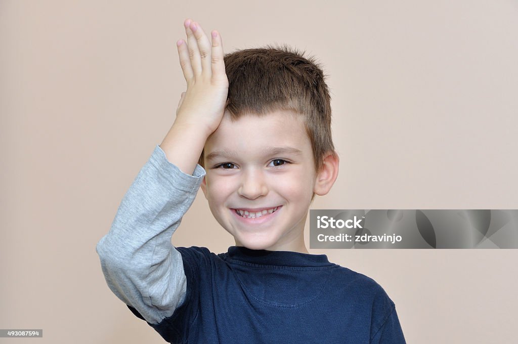 Young boy slapping hand on head Cute young smiling boy slapping hand on head  Child Stock Photo