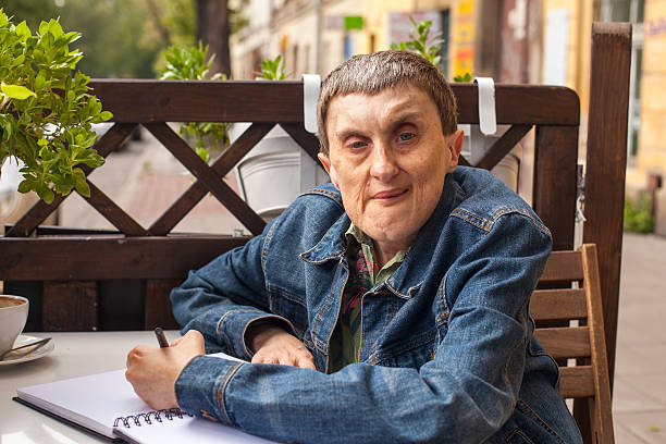 istock Adult disabled man with cerebral palsy sitting with a notebook 493088352