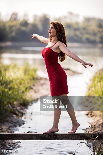 Happy Woman Balancing On Wooden Post Above The Stream Stock Photo - Download Image Now