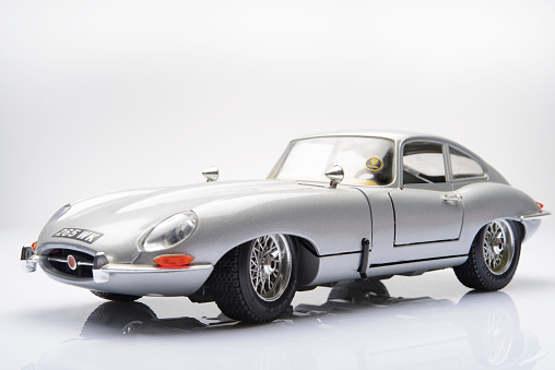 Kampen, The Netherlands - March 25, 2014: Jaguar E-Type classic sports car model by Bburago isolated on a white background. The Jaguar E-Type or Jaguar XK-E is an iconic British sports car, which was produced by Jaguar Cars between 1961 and 1975.