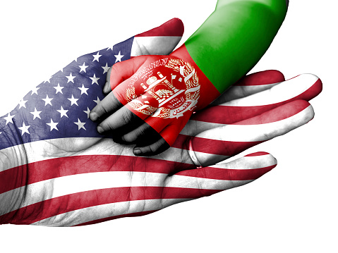 Flag of United States overlaid the hand of an adult man holding a baby hand with the flag of Afghanistan overprinted. Conceptual image for help, aid, assistance, rescue. Isolated on white background