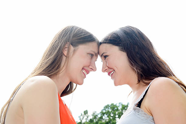 Women friends lying face up on the lawn of a park. They are happy and enjoying a beautiful day.