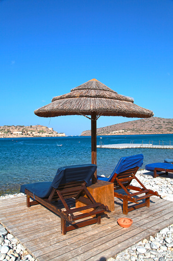 Two lounge chairs with sun umbrella on a beach, vertical image