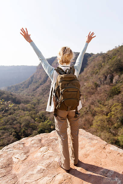 istock female hiker arms open on mountain cliff 493116222