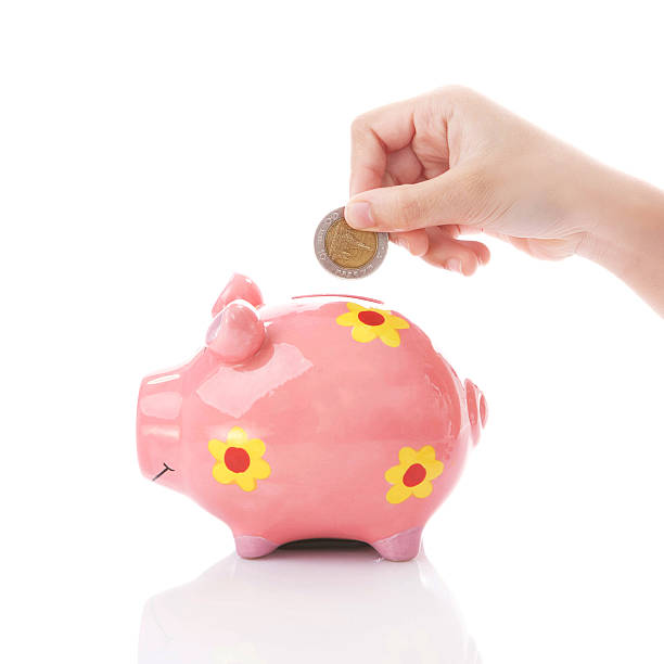 istock Kid hand putting a coin into piggy bank 493119482