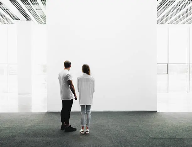 A man and woman walking through on the exhibition hall and examines the gallery of the exhibition 