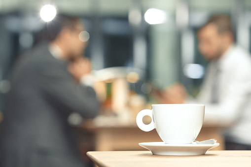 Cup of coffee on a table with a business partners in the background