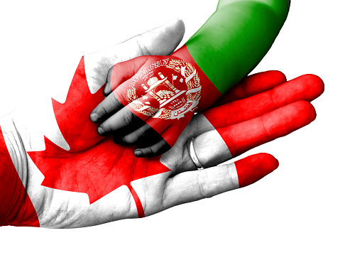 Flag of Canada overlaid the hand of an adult man holding a baby hand with the flag of Afghanistan overprinted. Conceptual image for help, aid, assistance, rescue. Isolated on white background