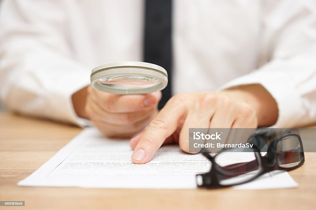 Focused businessman is reading through  magnifying glass document Artificial Stock Photo