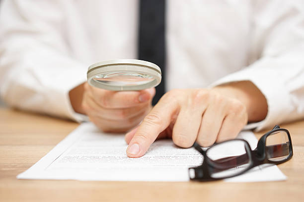 Focused businessman is reading through  magnifying glass document stock photo
