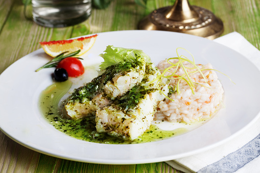 white fish with pesto sauce and meat on a plate in a still life gourmet restaurant menu