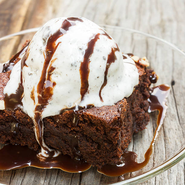 A brownie with a scoop of vanilla ice cream and hot chocolate sauce dribbled all over it, called ¨Death by Chocolate¨