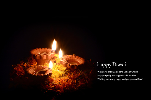 Clay diya lamps lit during diwali celebration on black background. Greetings Card Design Indian Hindu Light Festival called Diwali