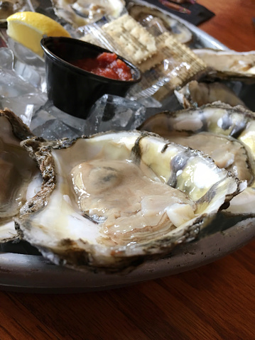 Ray oysters on the half shell with cocktail sauce and lemon served on an oyster plate with ice