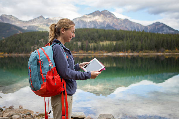 istock Young woman hiking by the lake using digital map 493180652