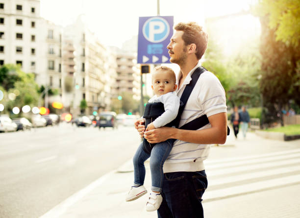 Portugal, Porto, 05 May 2018: A young father walks with his young children along a city street.