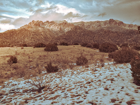 snow contrasts the desert terrain and mountain peaks.  horizontal mobilestock composition with retro color treatment taken in the sandia mountains of albuquerque, new mexico.