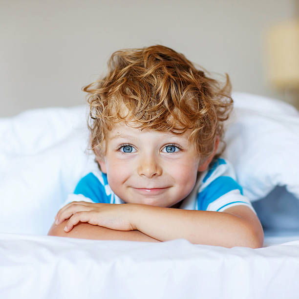 istock Adorable kid boy after sleeping in his white bed 493186452