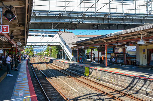 Nara Japan - October 8, 2015: Looking down the tracks at a small Train Station, Japan. Various people standing on the platforms waiting for trains.