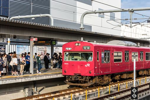 Osaka, Japan - October 8, 2015: A Japan Rail (JR) train at the platform at Osaka station. Various people queueing on the platform.