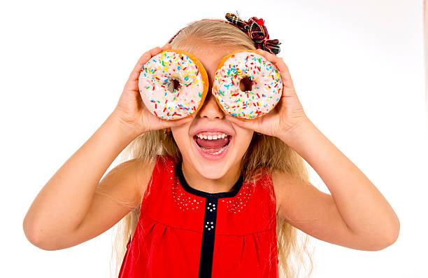 istock happy child playing with donuts in her eyes 493190996