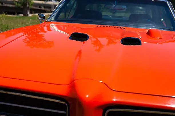 Detail of an orange 1969 Pontiac GTO car hood and hood scoops
