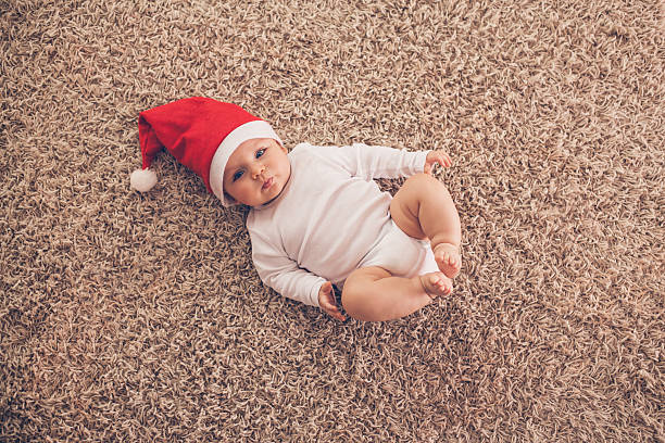 baby-junge mit weihnachtsmütze liegen auf dem teppich - carpet floor lying down people stock-fotos und bilder