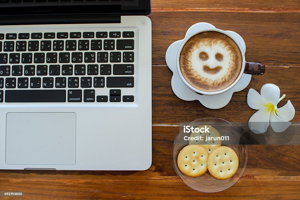 Laptop with sunshine shape coffee Laptop with sunshine shape coffee on the wood table 2015 Stock Photo