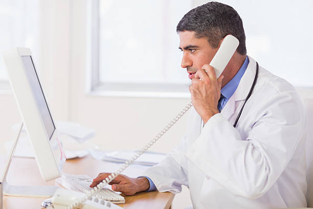 istock Concentrated male doctor using computer and phone 493201005