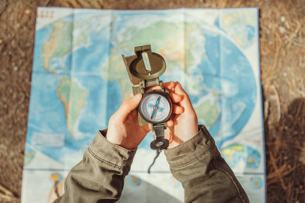 Traveler searching direction with a compass on background of map stock photo