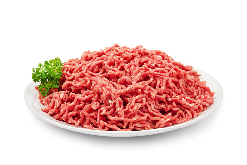 Plate with fresh raw ground beef isolated on white.