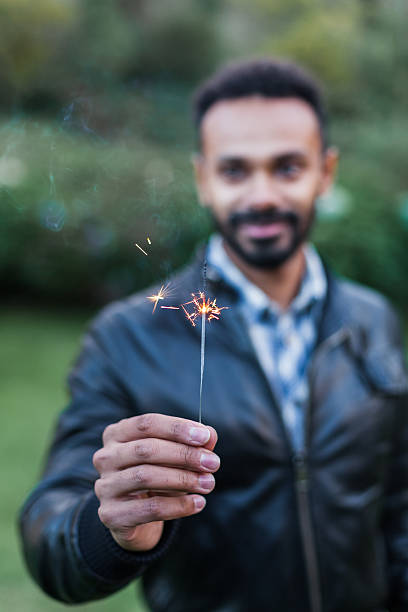 istock Young man holding a sparkler lit to celebrate new year 493209640