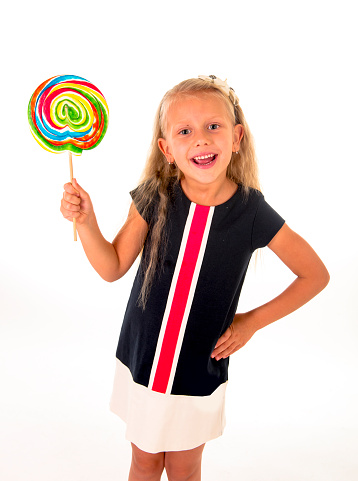 beautiful female child with long blond hair and blue eyes holding huge spiral lollipop candy smiling happy and excited isolated on white background in sugar and sweet concept