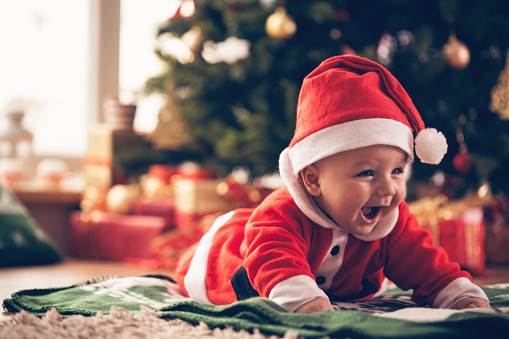 Cute baby luying down on the floor near Christmas tree.